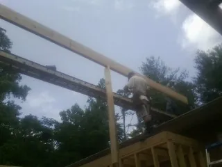 Carpenter setting a ridge beam over a new addition frame — Ice Dam Removal by Roofing Brothers in Calabash
