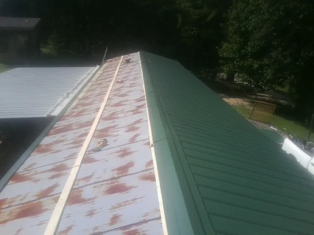 Old rusted panels beside newly installed green metal roofing — Wind Damage Roof Repair by Roofing Brothers in Calabash
