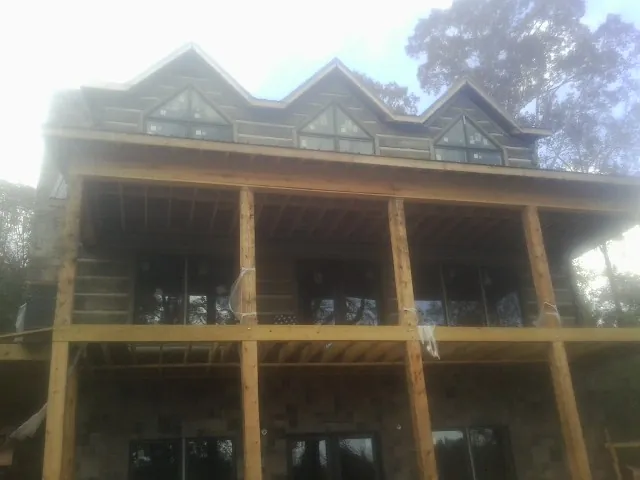 Dormers and porch framing on a large log home under construction — Roof Coating work by our crew in Calabash