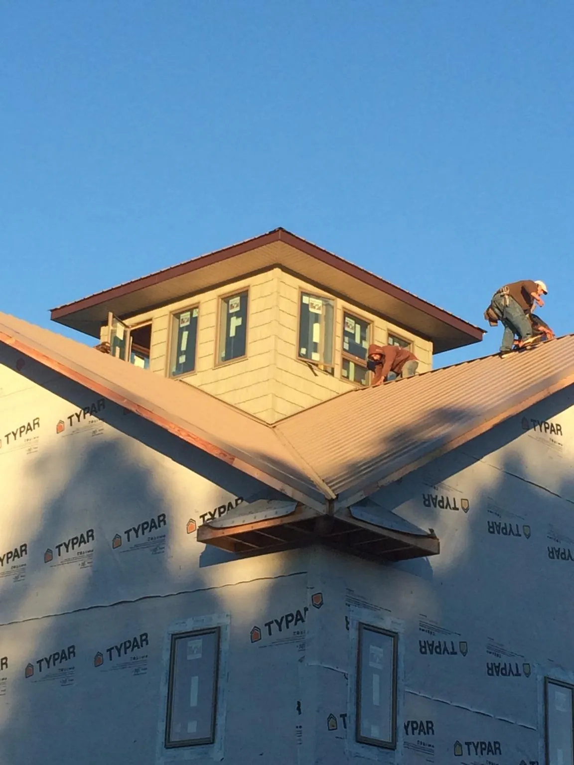 Roofers working around a rooftop cupola on a new metal roof at sunset — Roof Waterproofing in Calabash by Roofing Brothers